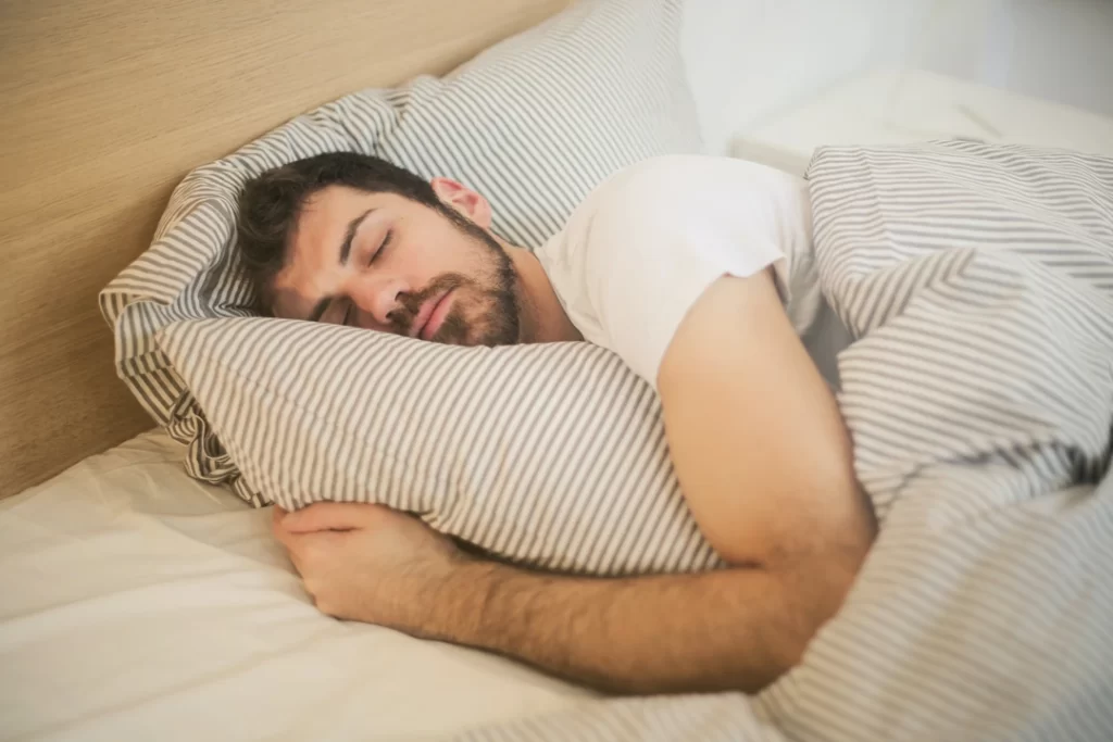 Man is cuddling his pillow while deep sleeping.