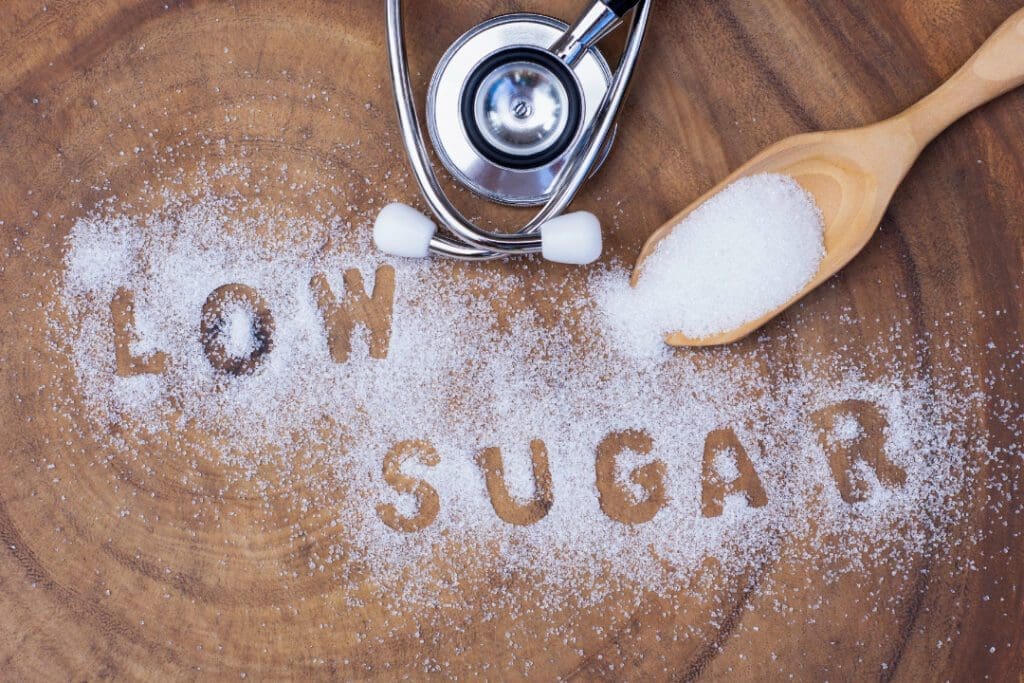 Low sugar is written with sugar on wooden background.