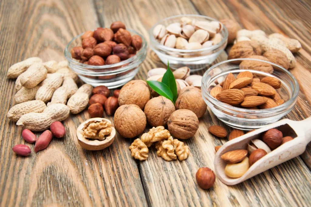 Almonds, Peanuts and other nuts and dry fruits on a wooden table.