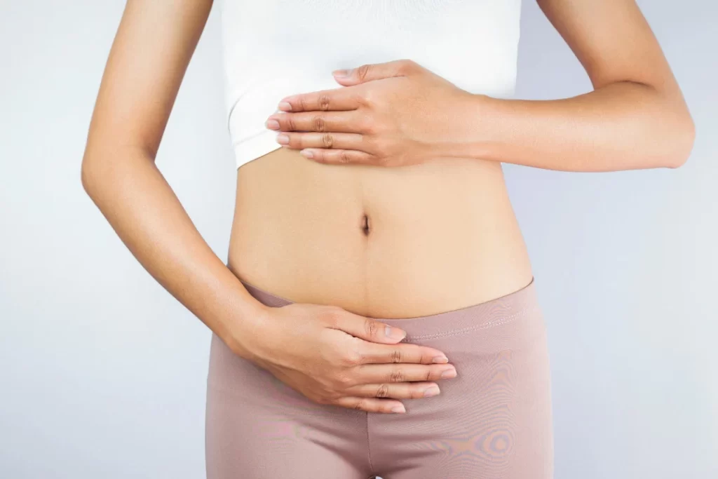 Woman shows a healthy gut with her hands around her belly.
