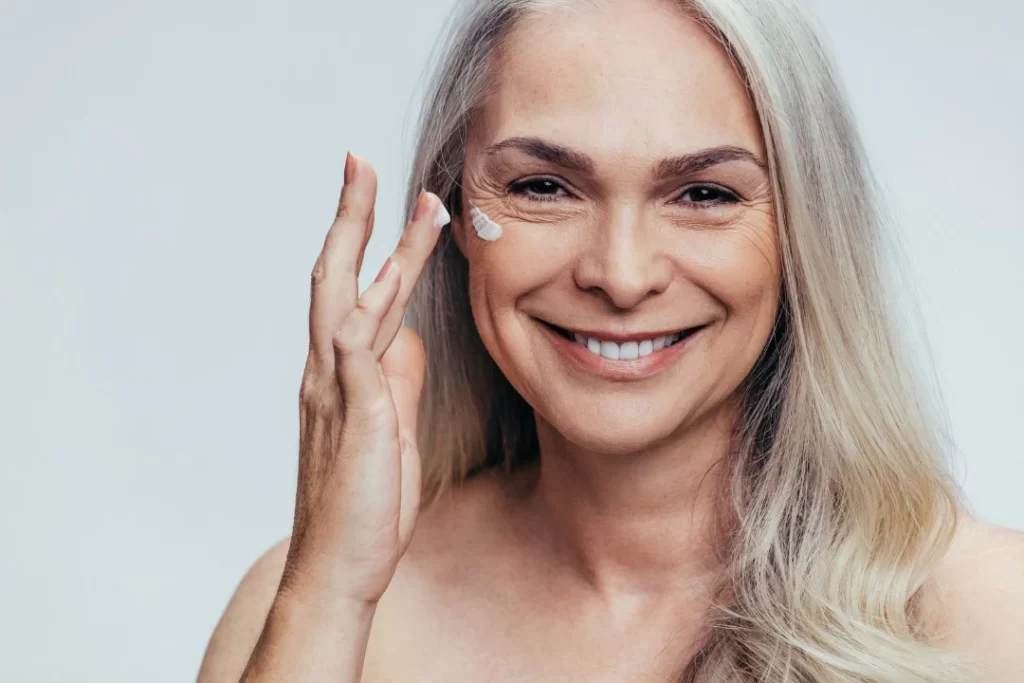 Attractive woman applying anti-aging cream on her face. 