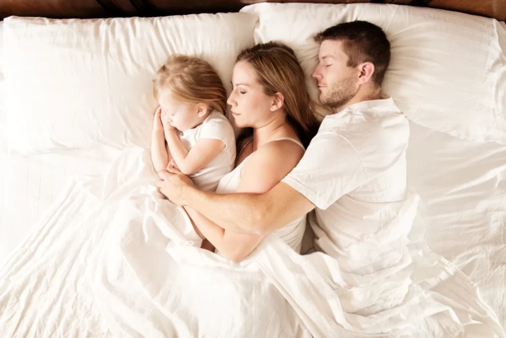 Family sleeping on the bed. 