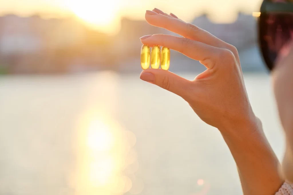 yellow gel capsule vitamin d omega 3 in woman's-hand.
