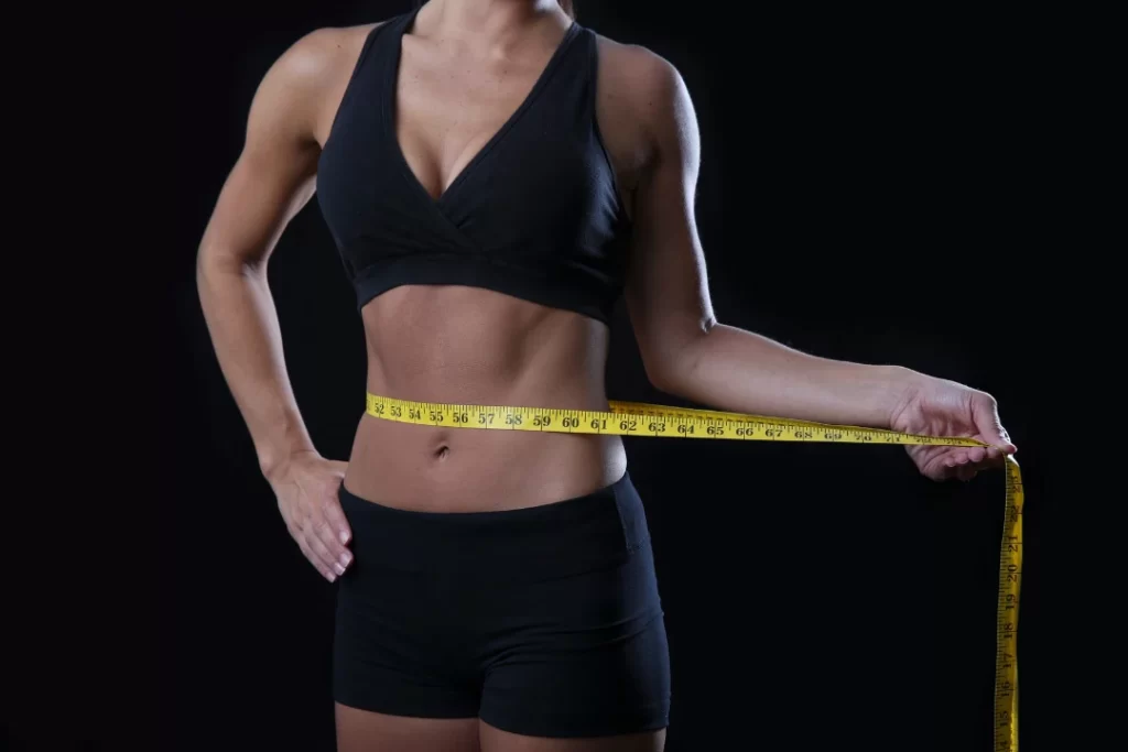 fitness girl with an inch of tape showing that she losses weight