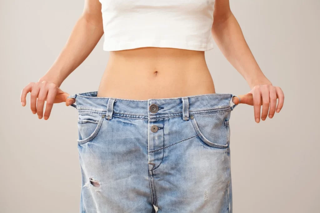 woman holding pants showing that she lost weight. 