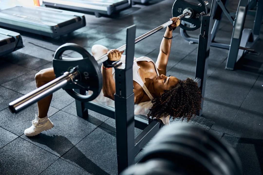 Fit woman bench pressing at gym.