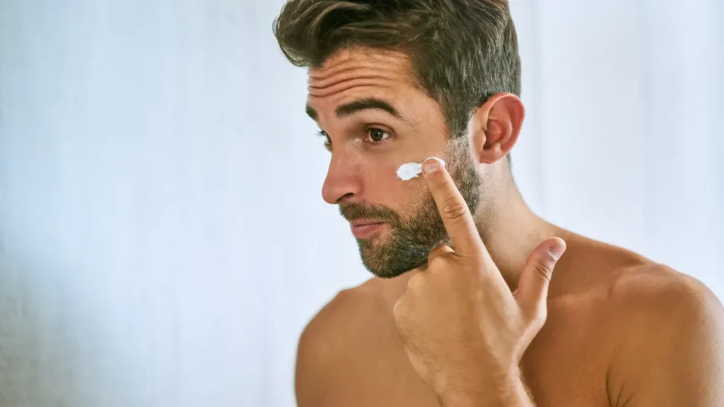 Man applying cream on his face. 