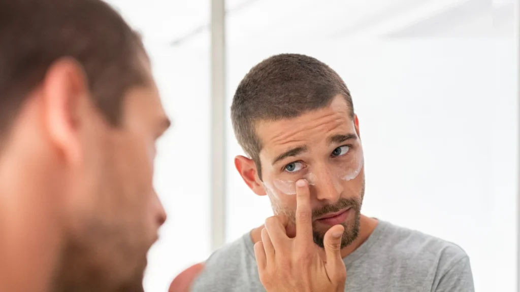 Man applying eye cream under his eye's